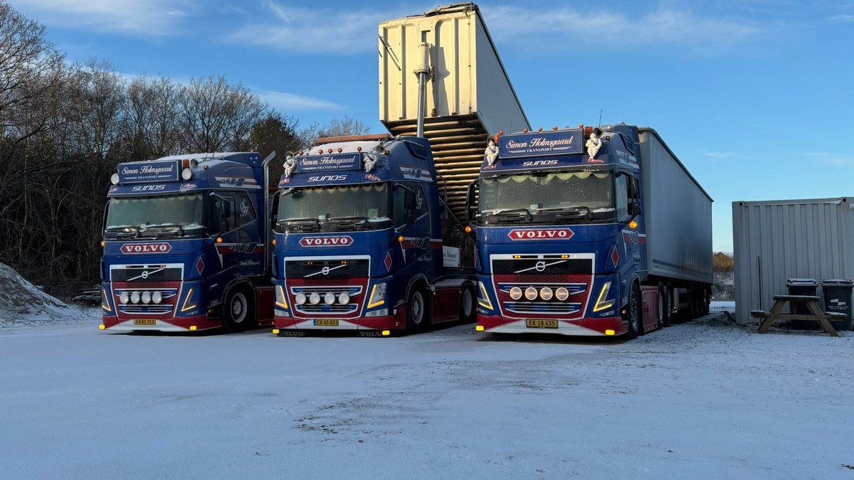 Tre af Simon Holmsgaard Transports Volvo-lastbiler holder side om side en vinterdag.