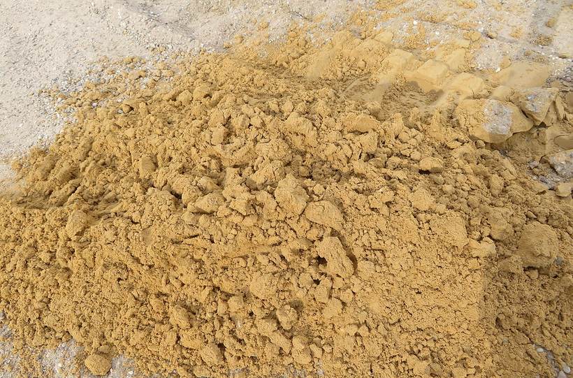 Bunke af gulligt sand på en materialeplads.